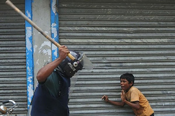 Criança sendo espancada por policial em protesto em Bangladesh, em 2010.