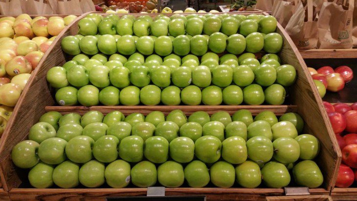 maçãs verdes arranjados em uma prateleira em um shopping 