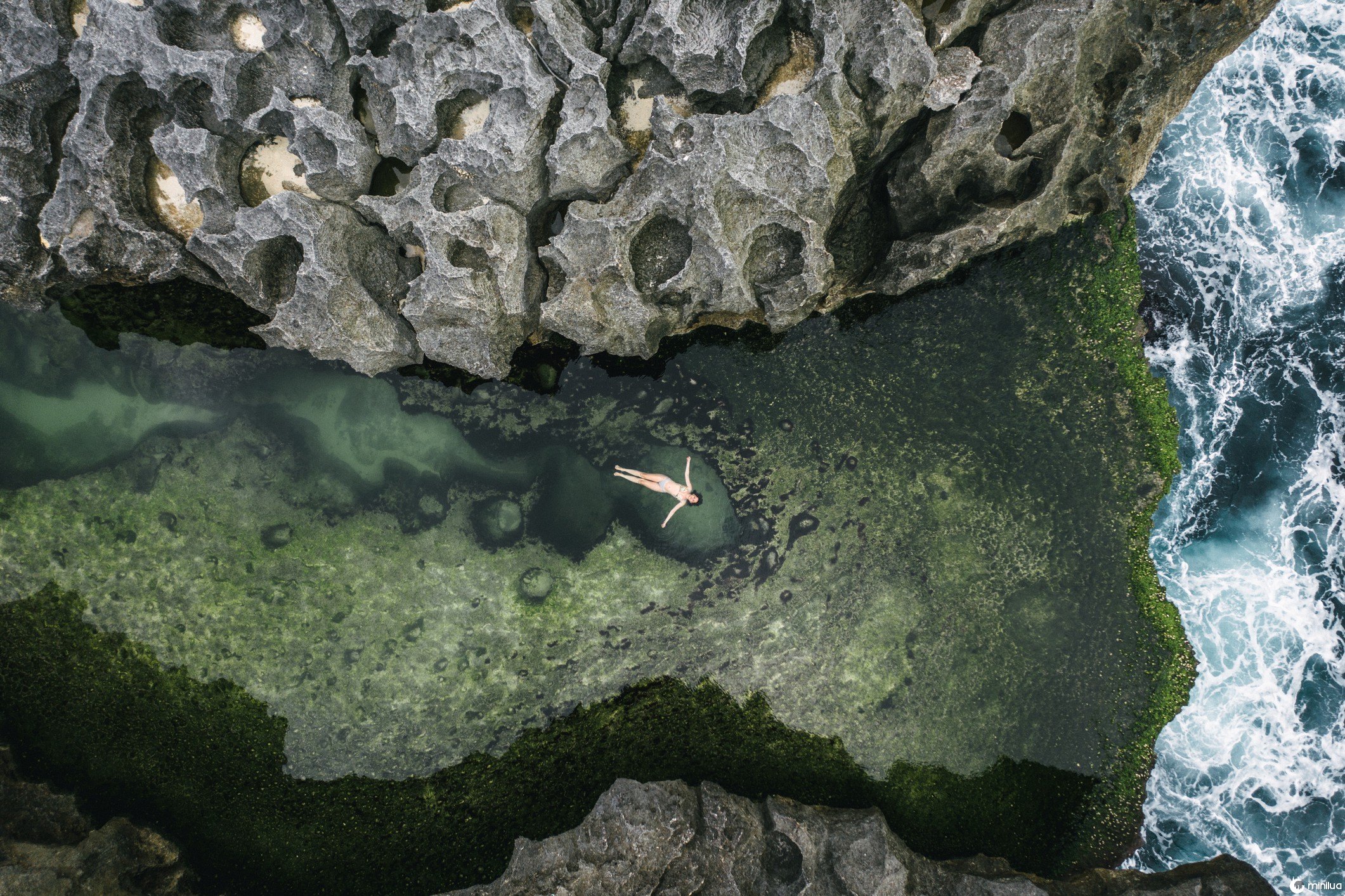 An overhead photo of a person floating along a reef.