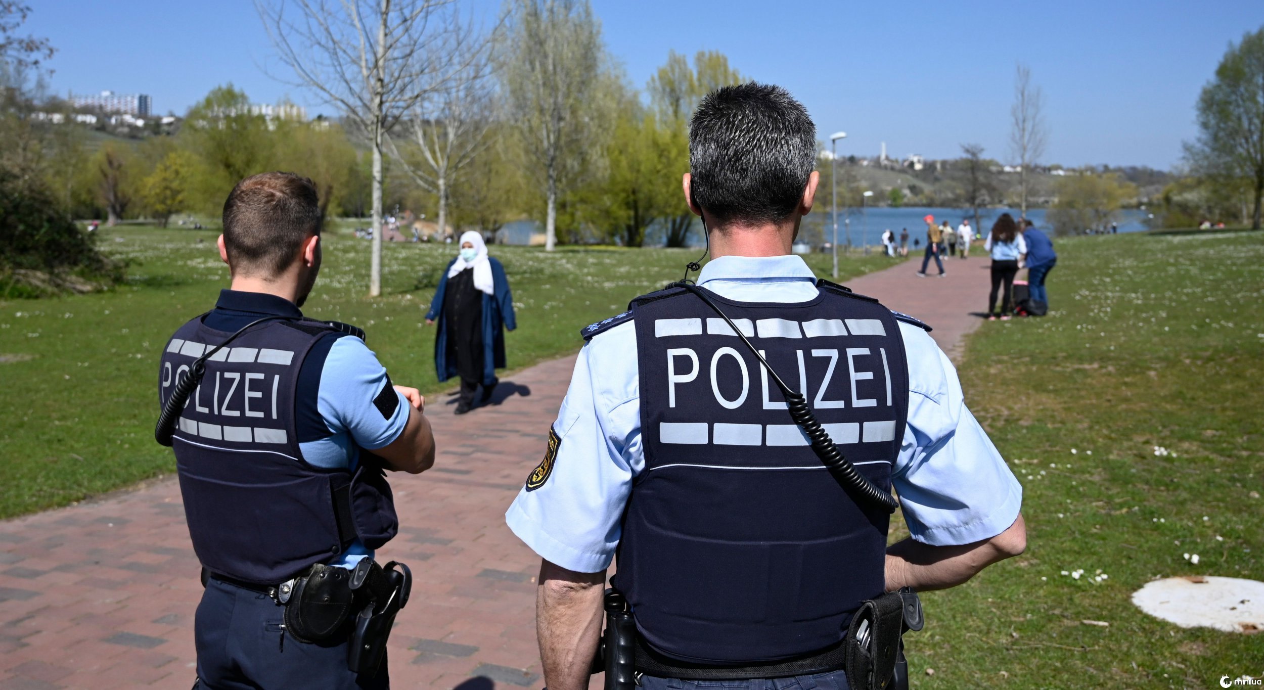 Police officers watch the situation at the lake Max Eyth in Stuttgart, southern Germany, on April 5, 2020, where numerous people enjoy the sunny weather amid the new coronavirus / Covid-19 pandemic. (Photo by THOMAS KIENZLE / AFP) (Photo by THOMAS KIENZLE/AFP via Getty Images)